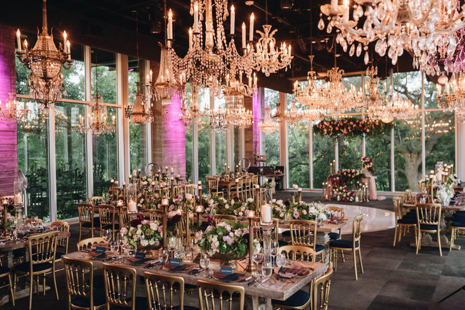 dining room with glittering chandeliers, floor-to-ceiling windows, and pink uplighting | PartySlate