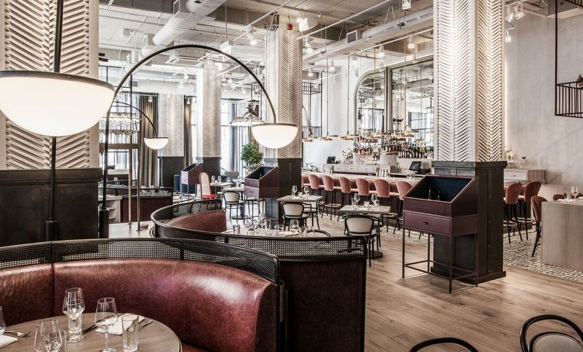 Elegant restaurant in natural light with cozy booths, low hanging floor lamps and red stools around the bar | PartySlate