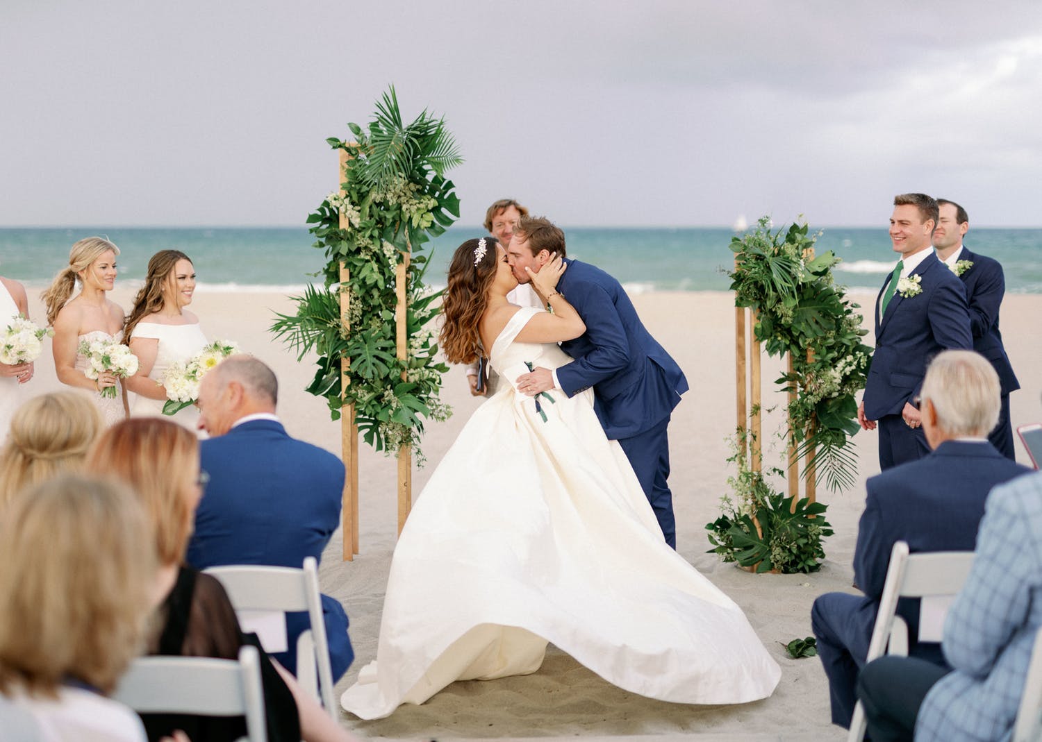 bride and groom kissing at beach ceremony