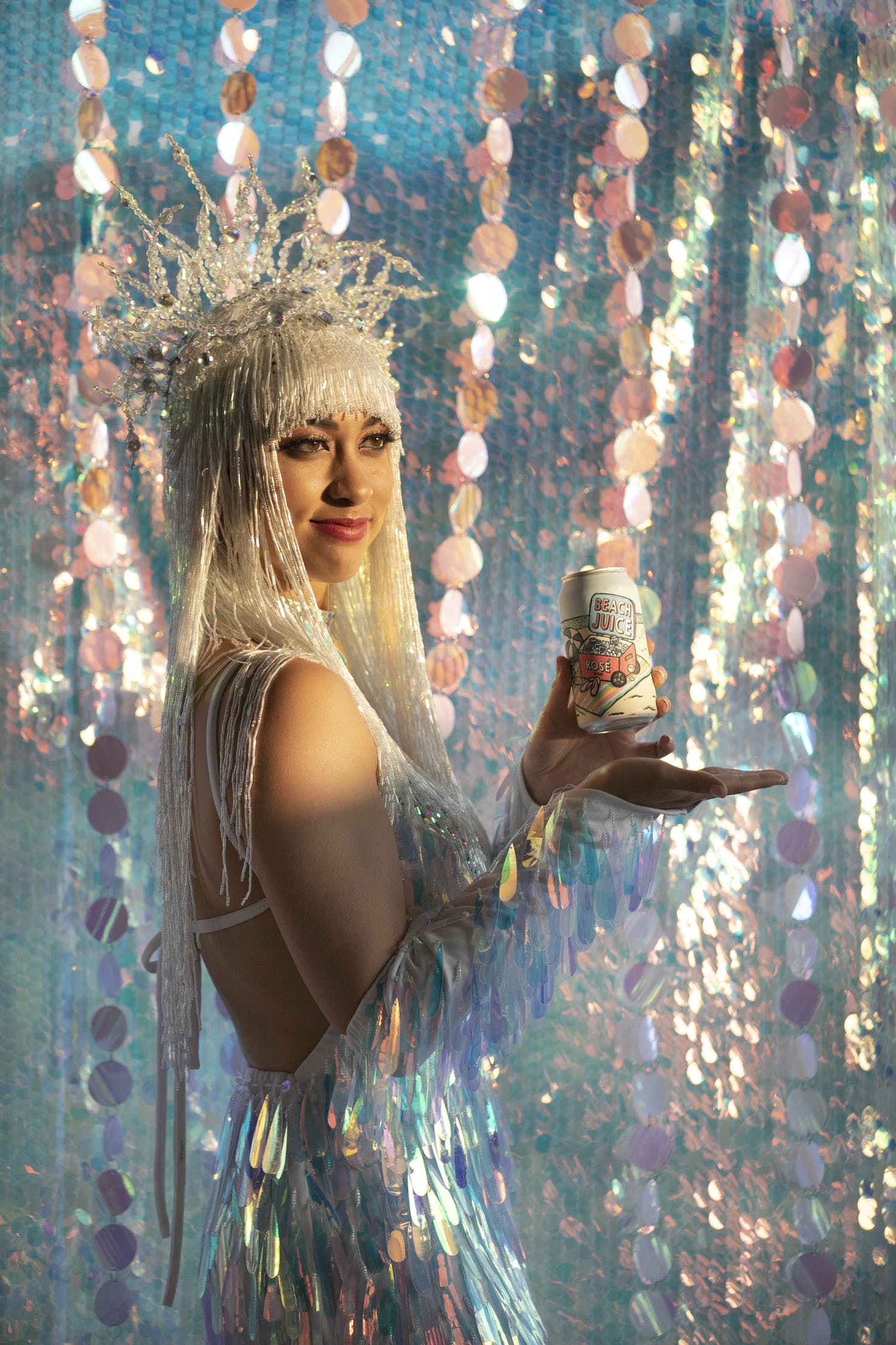 Woman holding beer can against a backdrop of iridescent décor