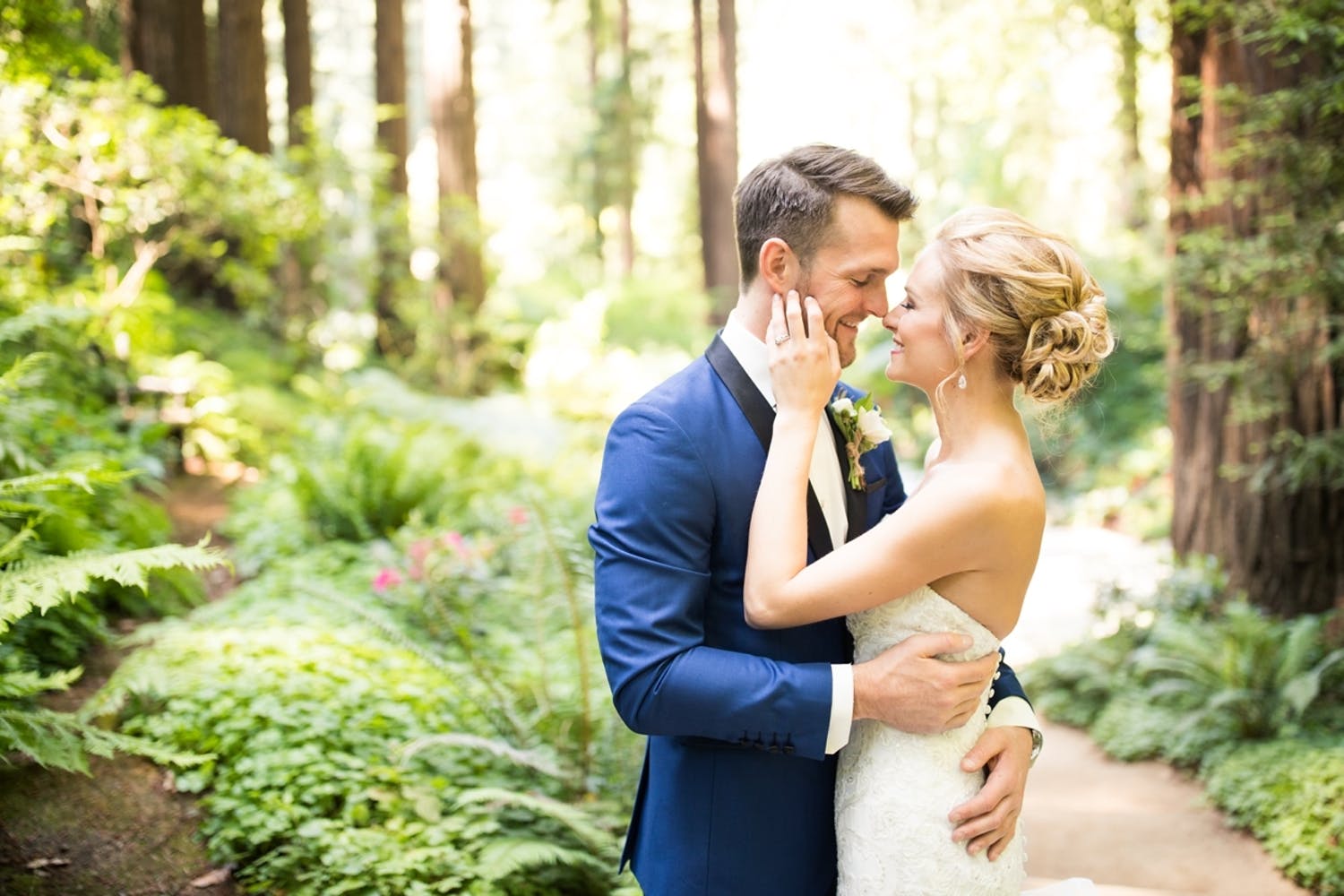 bride and groom about to kiss against forest backdrop