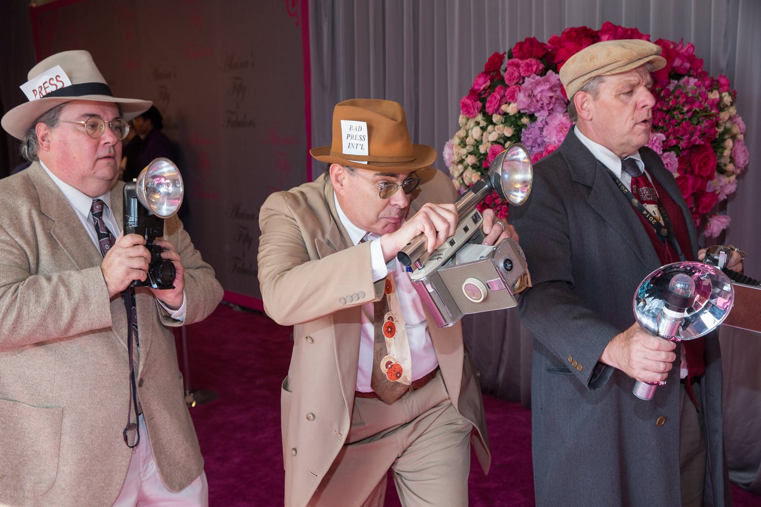 Three men dressed as paparazzi photographers