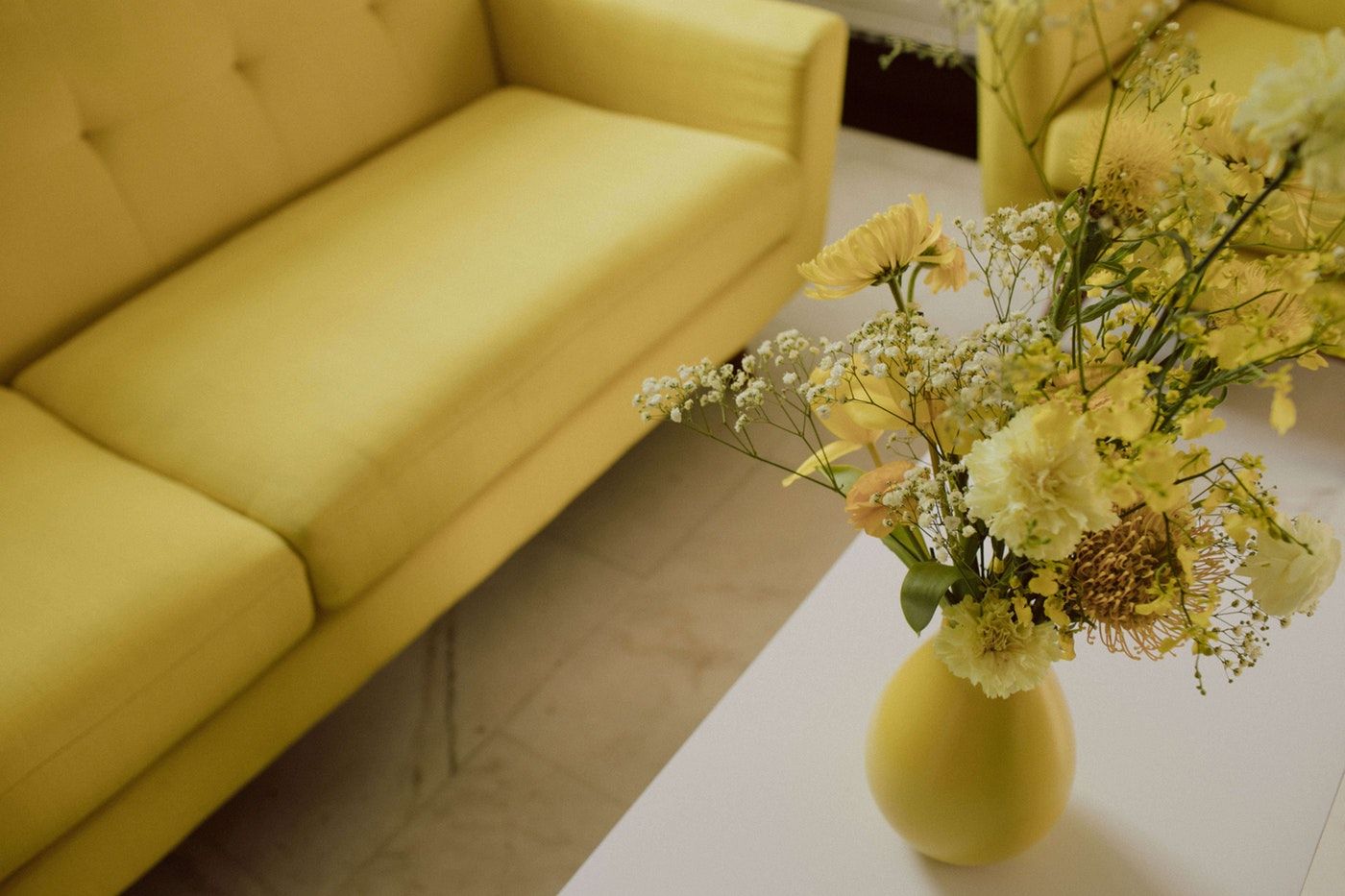 Yellow monochromatic event with a yellow couch and yellow floral centerpiece