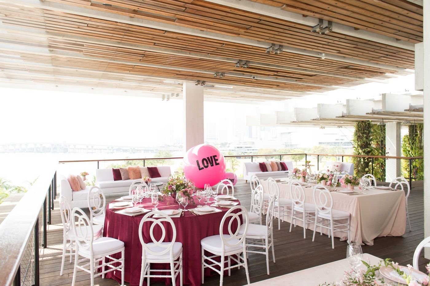 Party with white dining chairs, pink tablecloth, and a hot pink balloon with the word LOVE