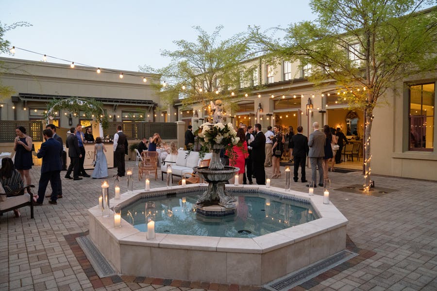 fountain surrounded by trees and people. Candles are placed throughout
