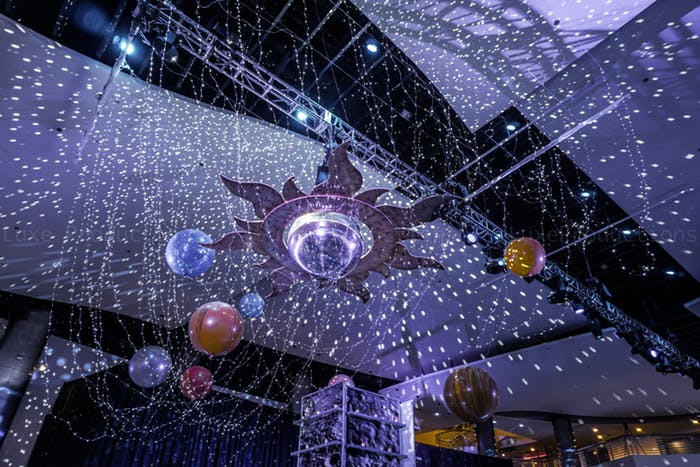 a solar system hangs above the crowd with silver tinsel around simulating a star filled sky.
