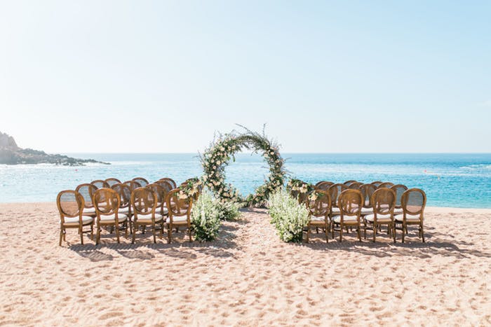 a circular arch on a beach with blue water in the background.