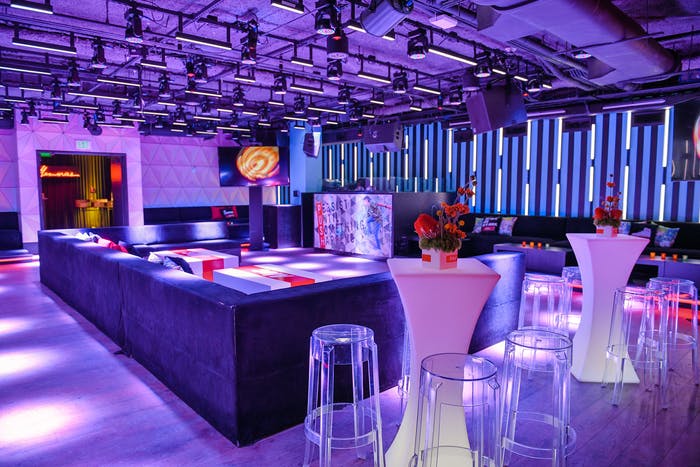 Purple ceiling with purple lighting on bar and high tops.