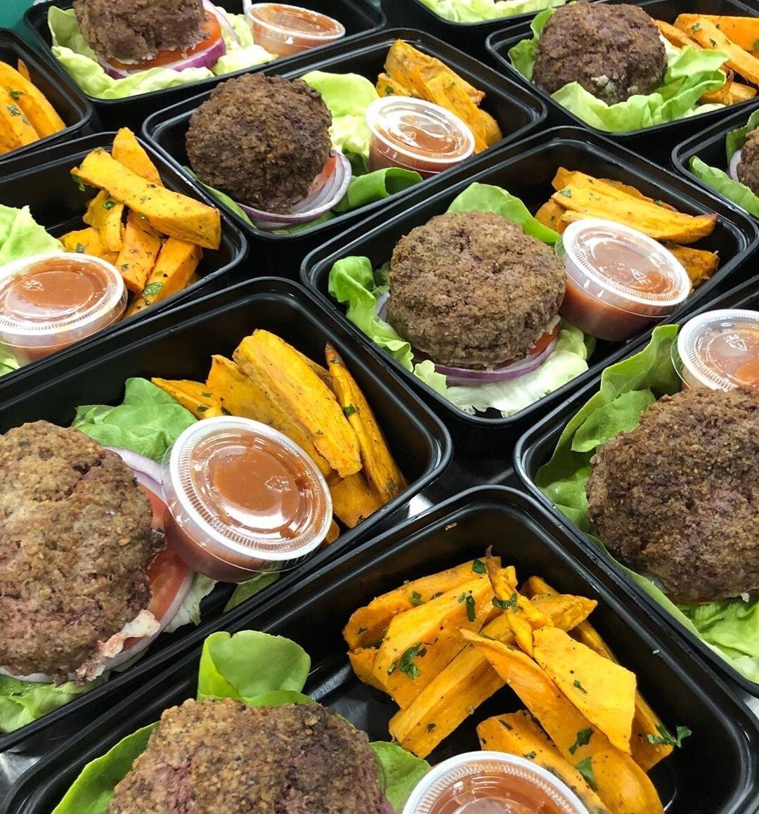 meals packed in black cartons without lids, they are all sitting next to each other