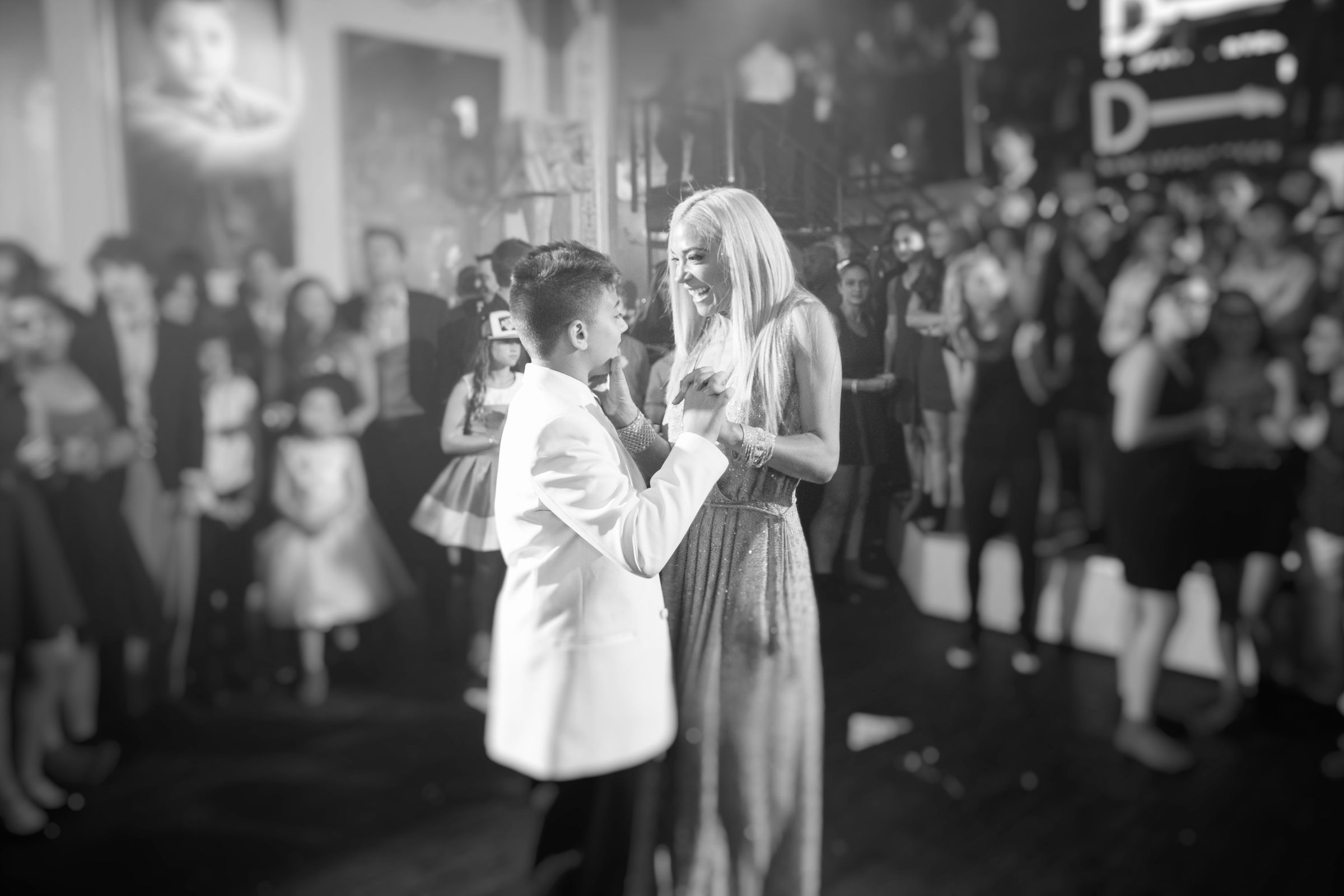 Mother lovingly ups her sons face as they dance surrounded by loved ones.