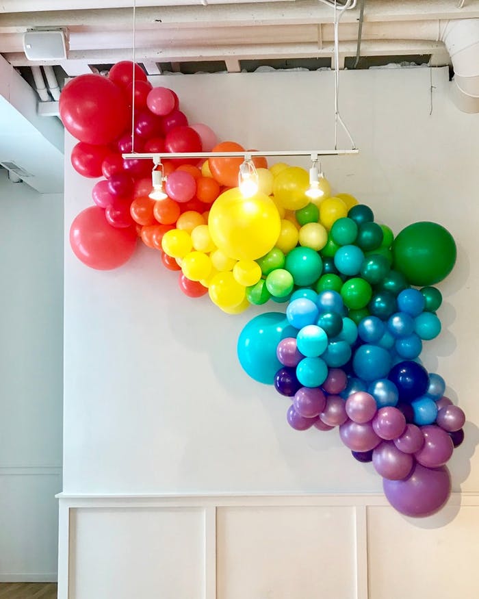 A diagonal cluster of balloons in varying sizes that descend in a rainbow