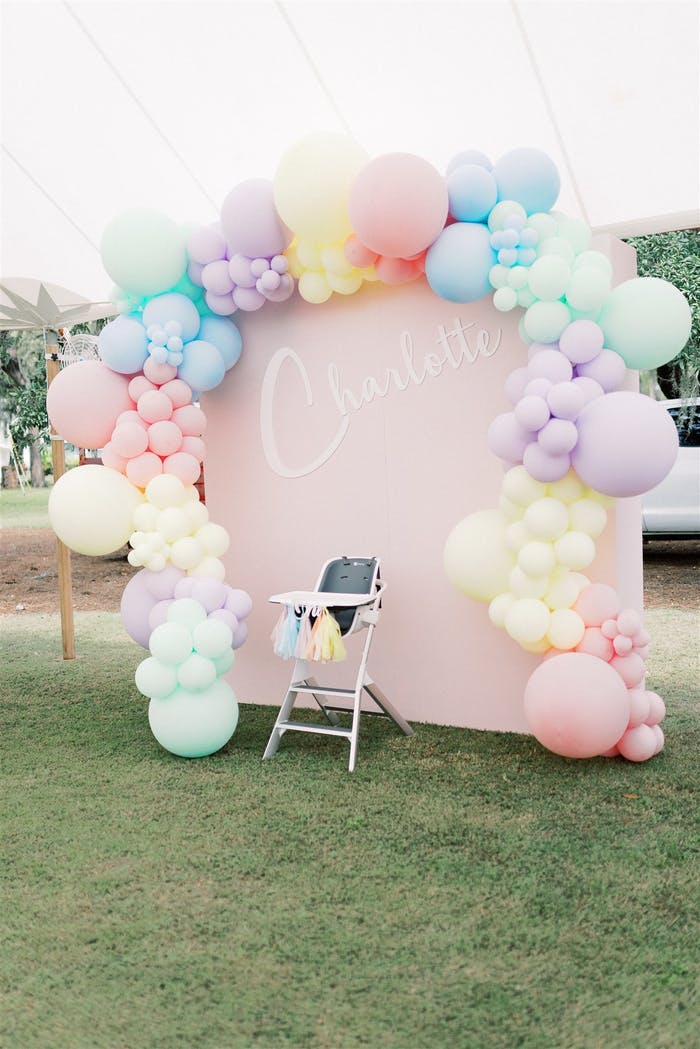 A dusty pink backdrop surrounded by different color pastel balloons.