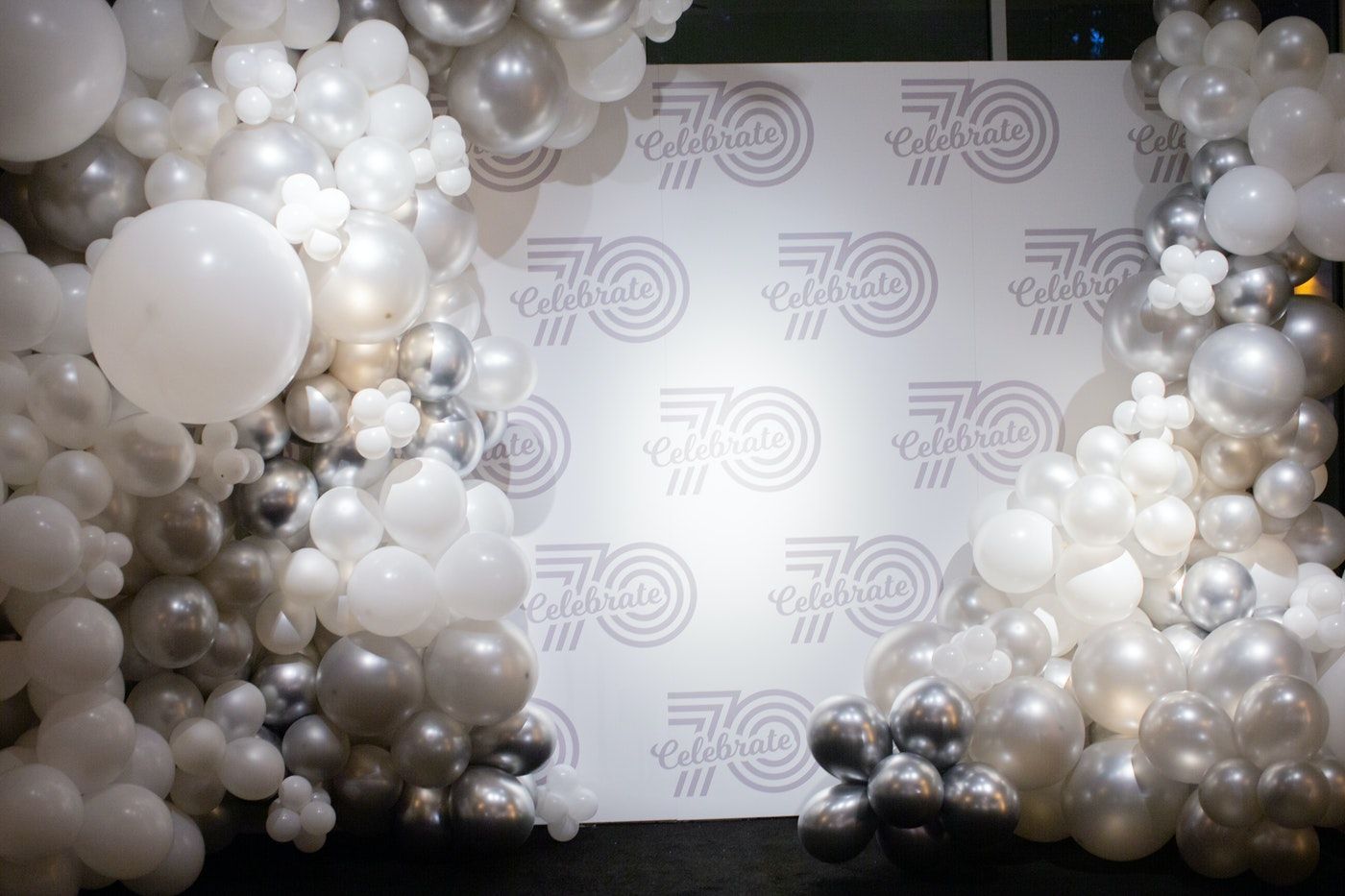 70th birthday photo-op backdrop with big white and silver balloons