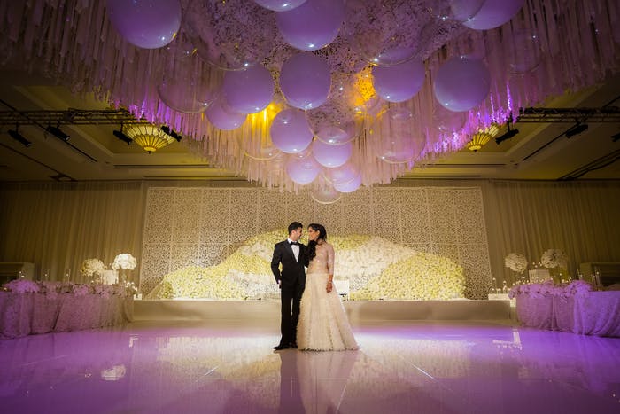 A couple standing on a dance floor. Purple and yellow lighting washes over the,,