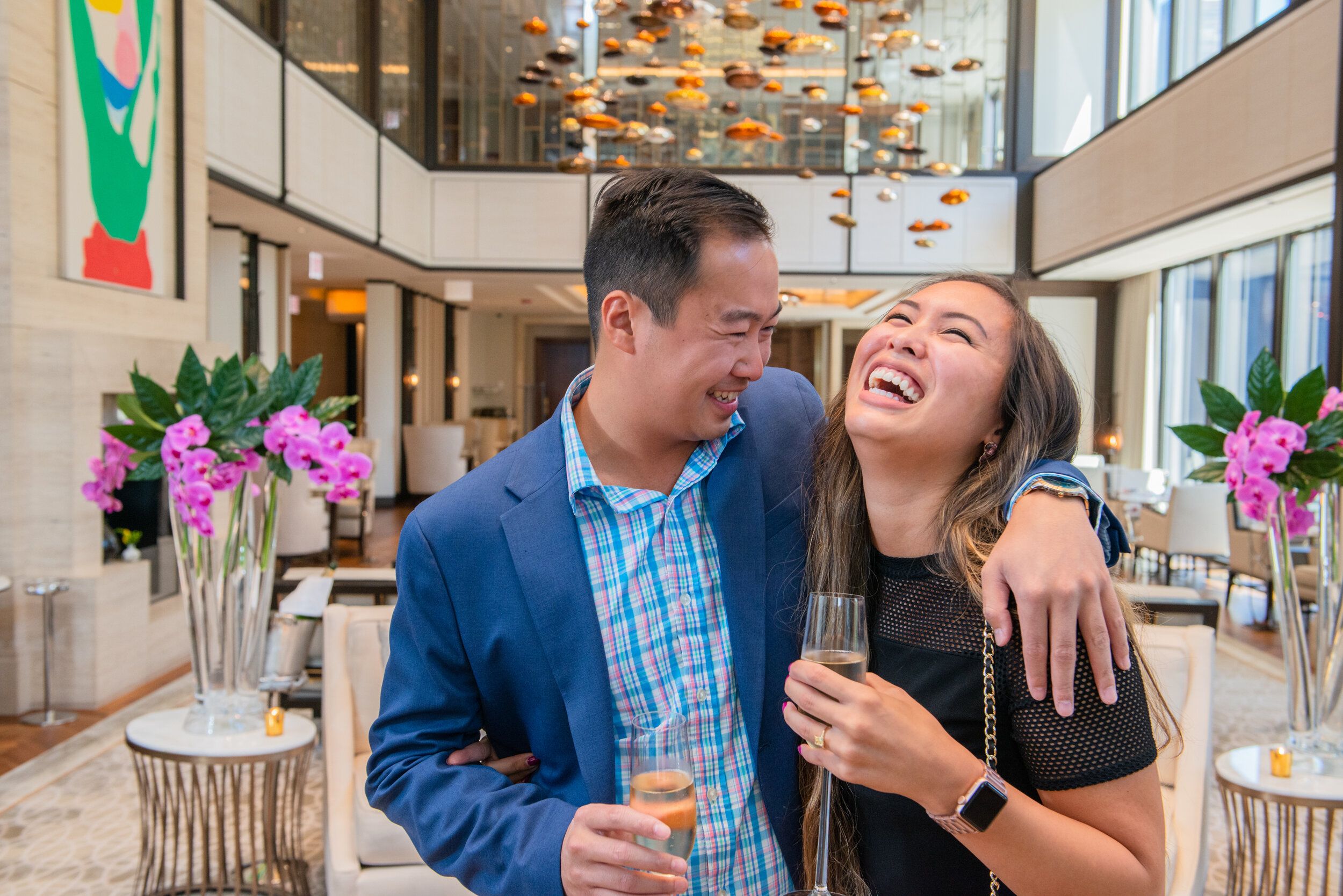 Couple laughs while holding champagne glasses.