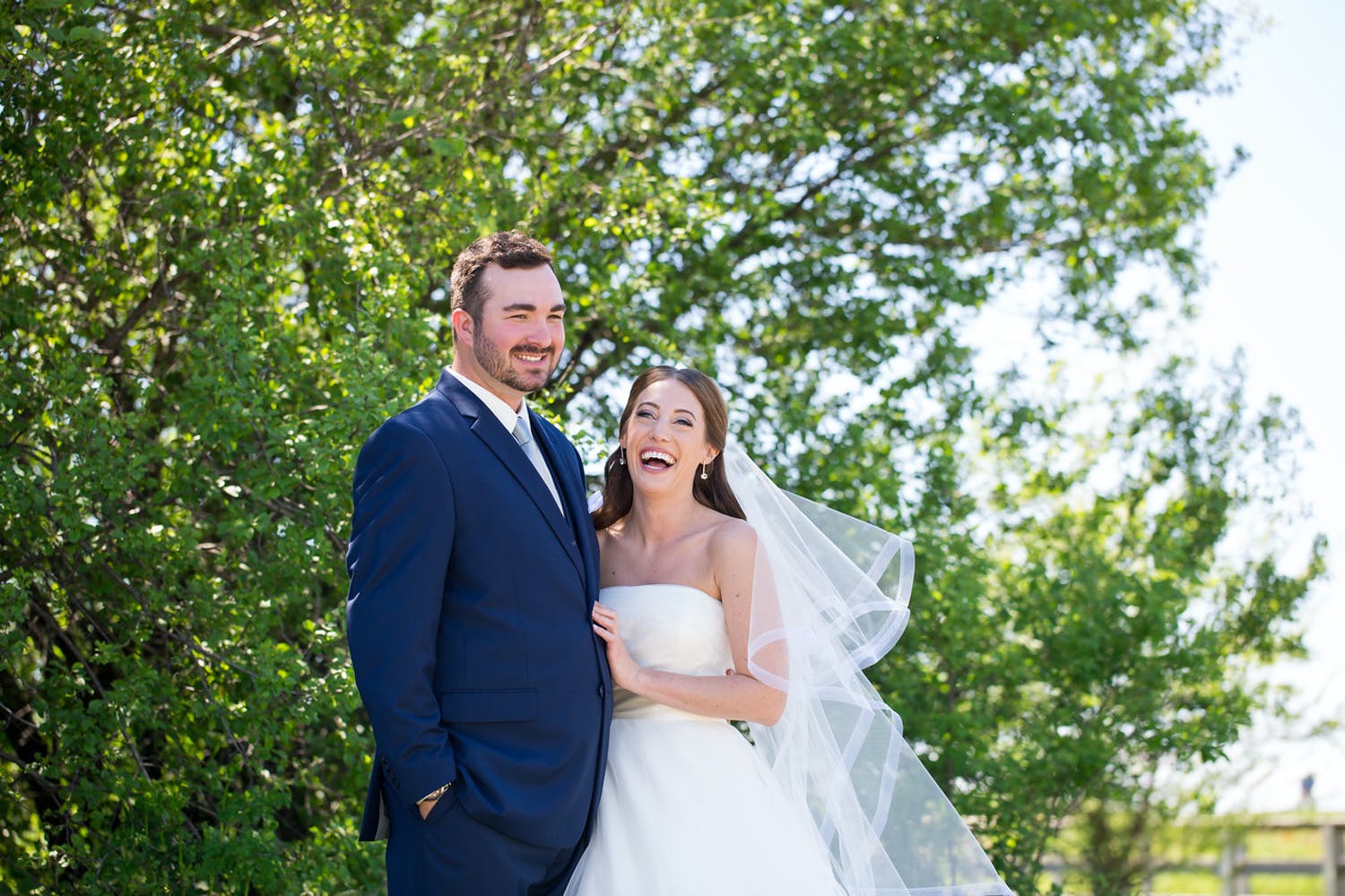 Portrait shot of bride and groom before summer tree.