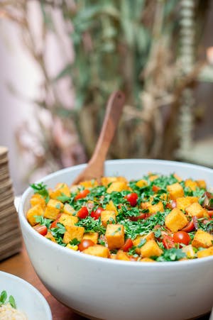 Side dish served in a white bowl with a wooden spoon | PartySlate