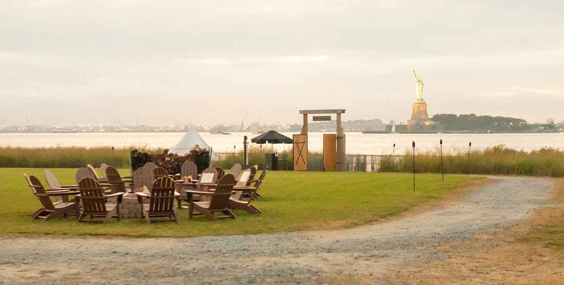 Far away shot from a campfire with a view of the statue of liberty | PartySlate