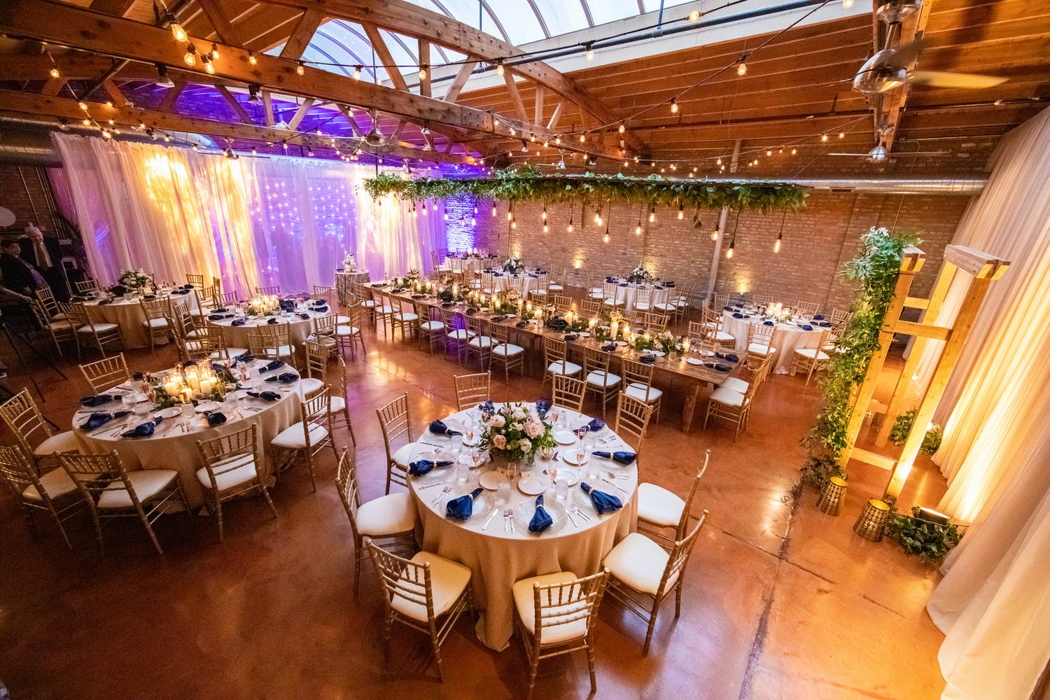 Wedding Reception at Loft on Lake in West Loop Chicago Featuring Green Foliage and Creative Wall Lighting | PartySlate
