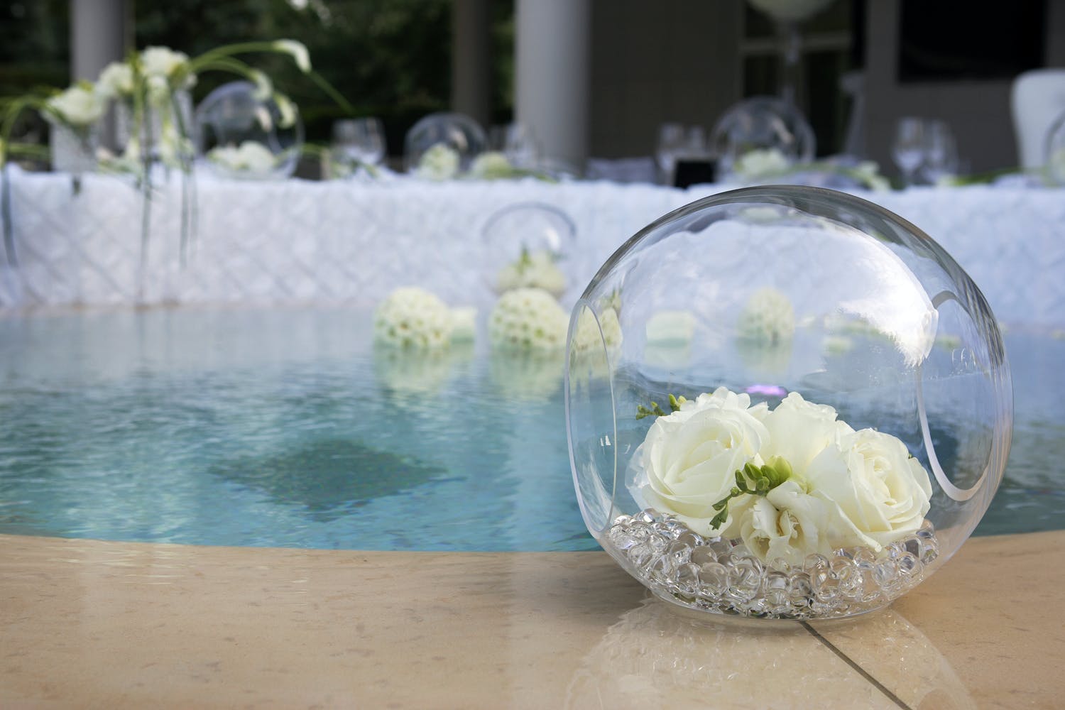 Poolside Décor With Glass Orbs Filled With White Flowers | PartySlate