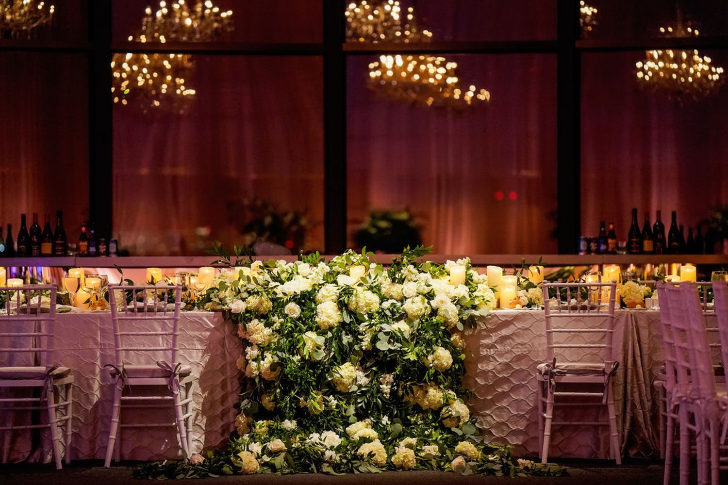Reception Table With Lavish Greenery Wedding Centerpieces Cascading Off Table | PartySlate