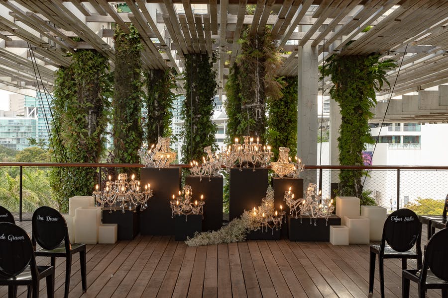 Wedding ceremony with chandeliers and greenery.