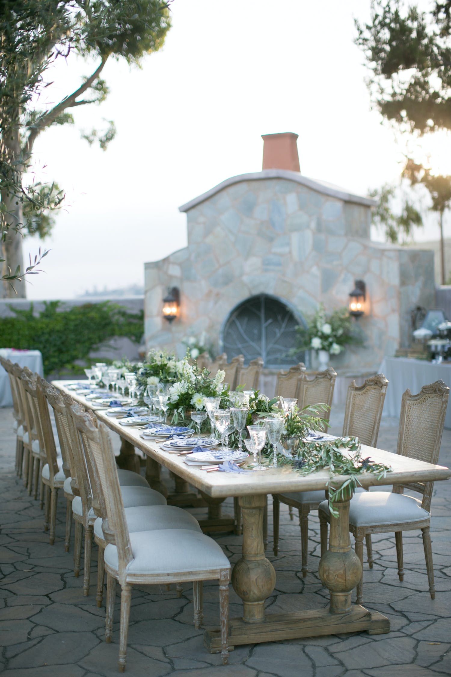 Outdoor dinner party with wicker chairs and garland draped table