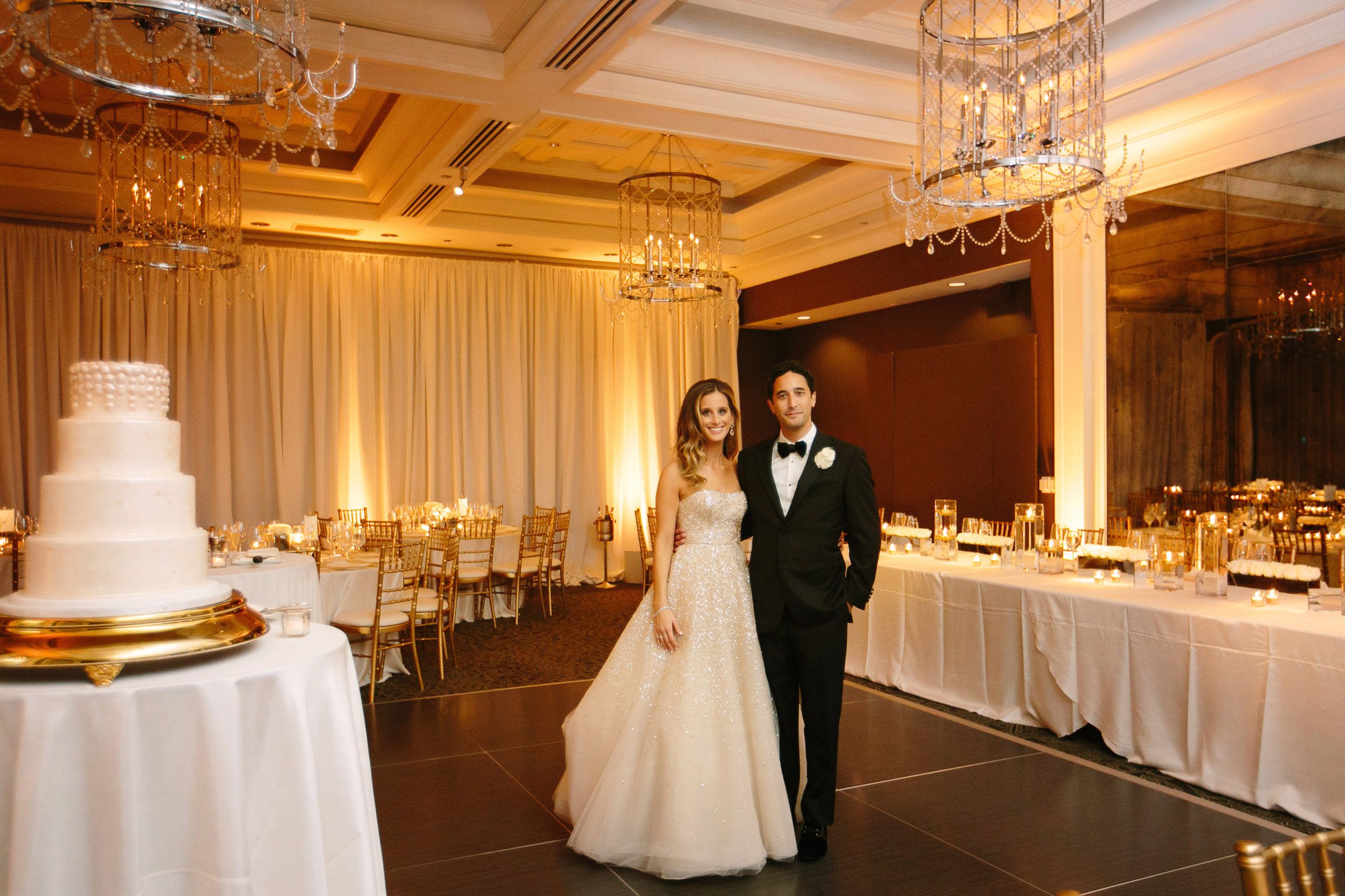 Bride and Groom Stand Behind White Wedding Cake in Ballroom at Waldorf Astoria Chicago Hotel | PartySlate