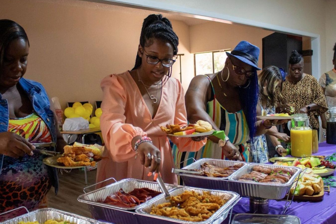Women serve themselves from buffet of Mama Tecia's Catering | PartySlate
