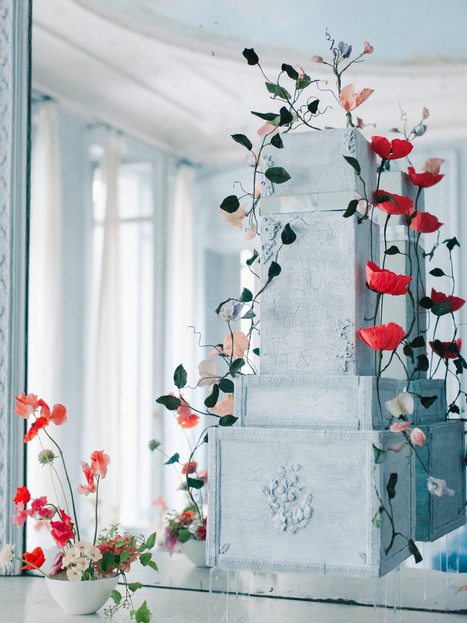 Large-block light blue cake with cascading floral and greenery vines on both sides | PartySlate