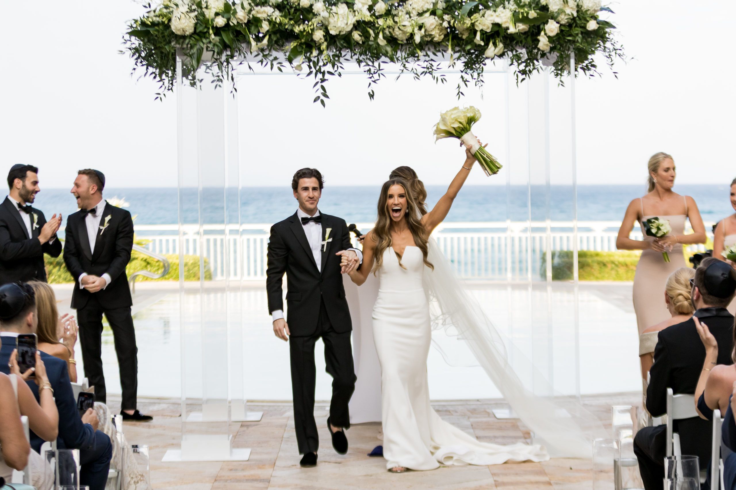 Classic and Tasteful Beach Wedding with Couple Walking Down the Aisle and Florals in Bride's Hand | PartySlate