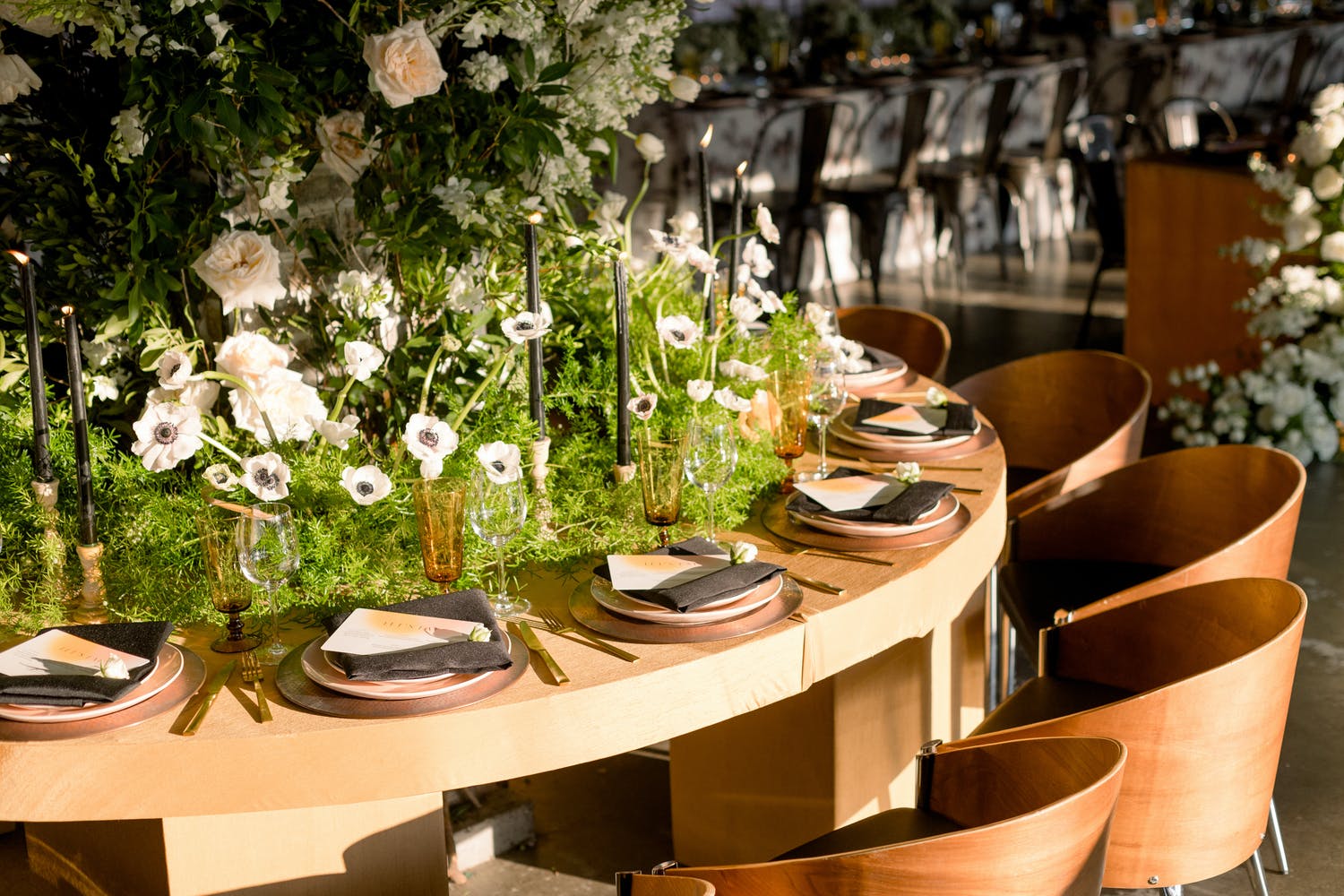 Wedding centerpiece of greenery and white flowers reaching all the way to each guest's place setting | PartySlate