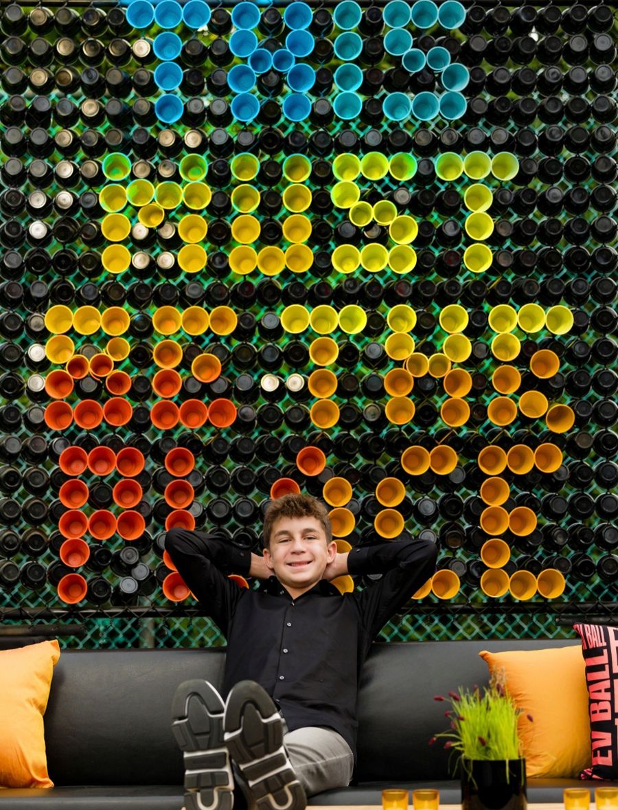 Bar Mitzvah Theme with Birthday Boy on Couch in Front of Personalized Colorful Sinage | PartySlate