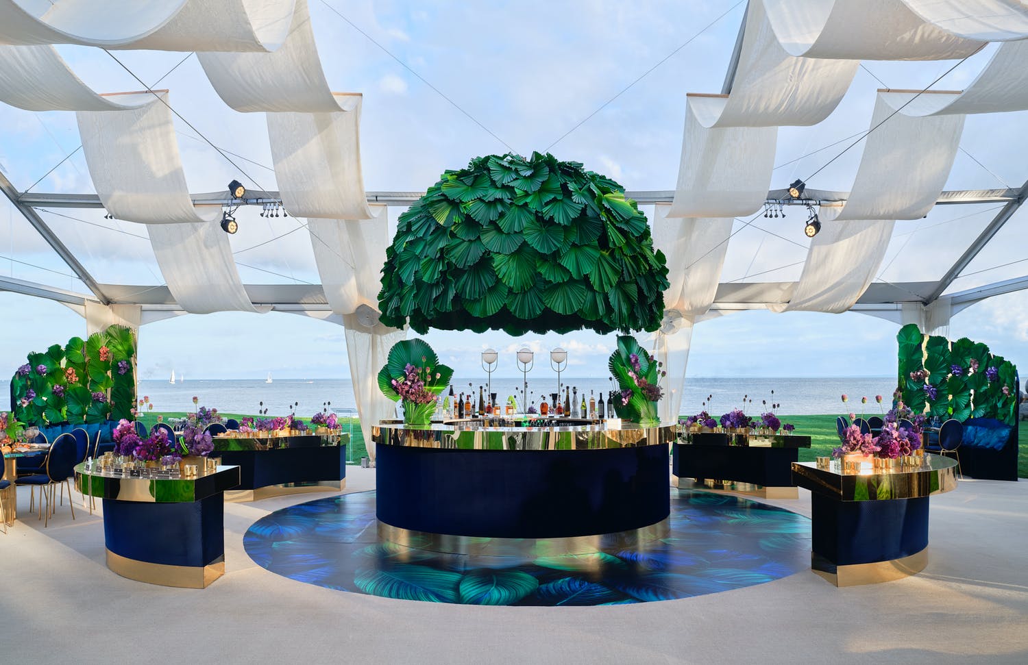 Seaside Bat Mitzvah under open tenting with white drapery and tropical bar set up with canopy of tropical foliage | PartySlate