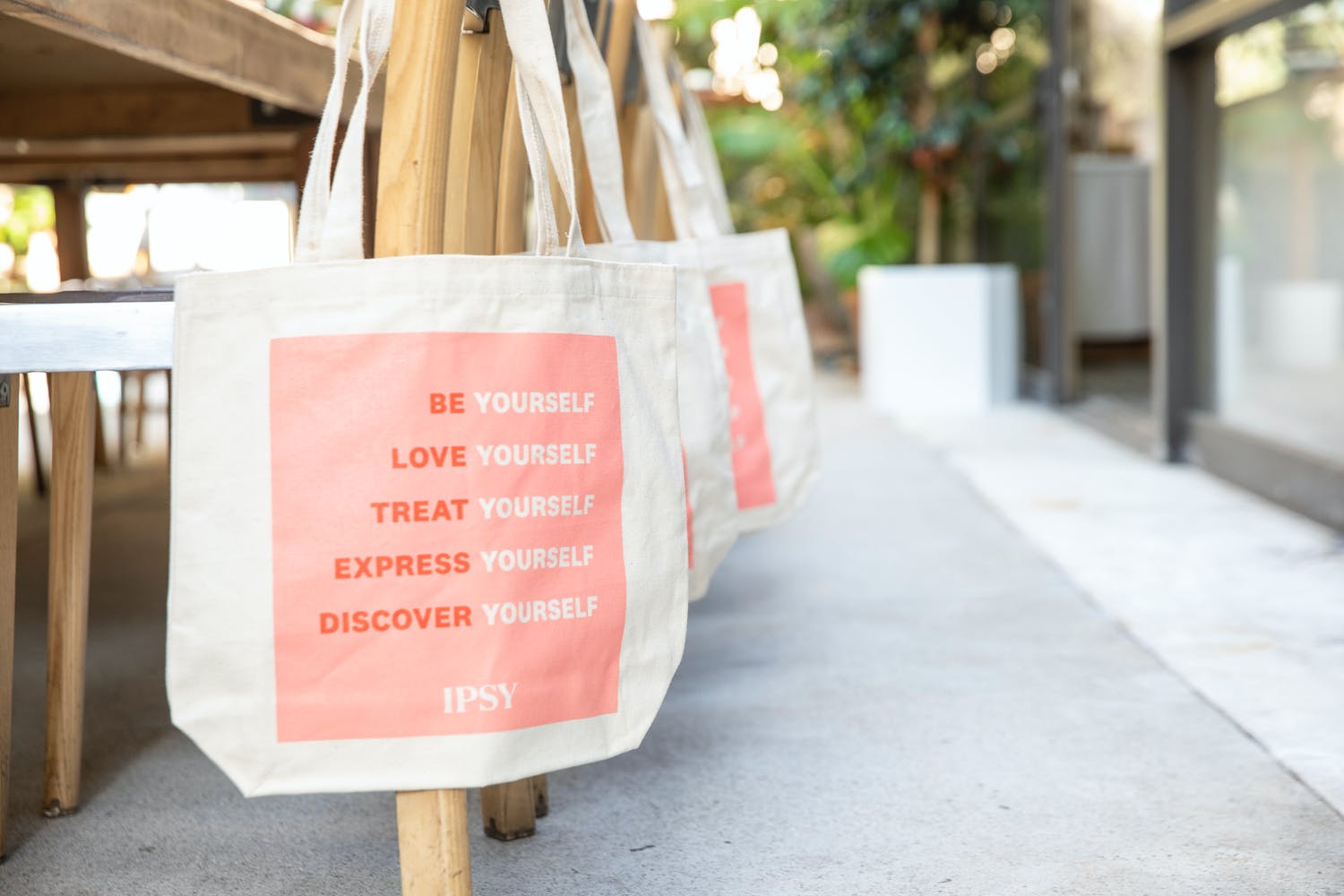 IPSY swag bags on reception table chairs at pastel pink product launch event | PartySlate