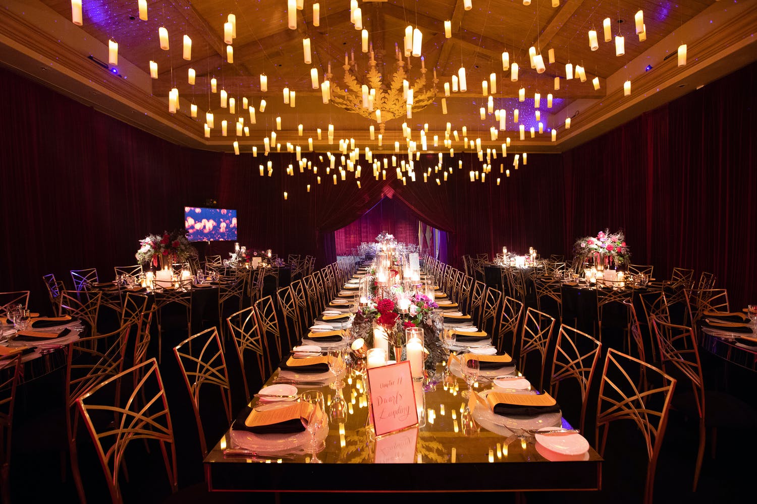 Wedding reception with floating candle ceiling installation and mirrored tabletops | PartySlate