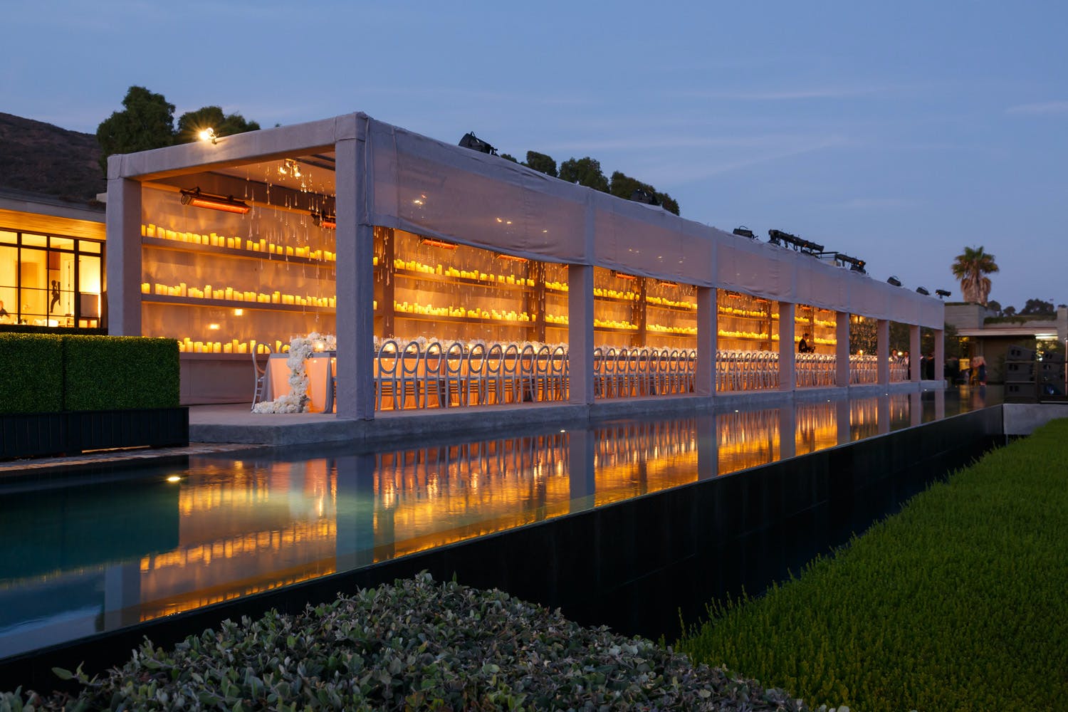 Custom-made poolside canopy with three tiers of candlelight for outdoor wedding reception | PartySlate