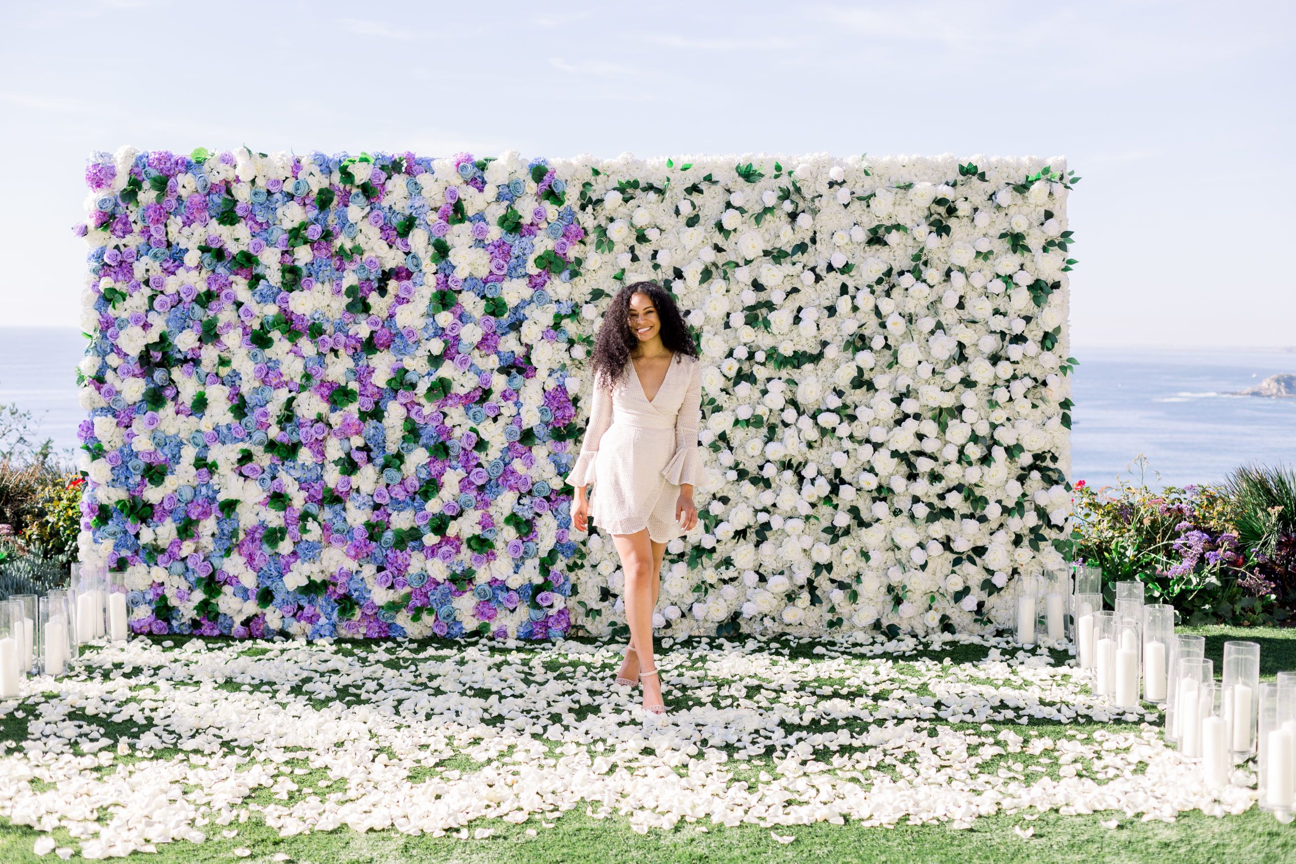 A women in front of a white and purple floral backdrop.