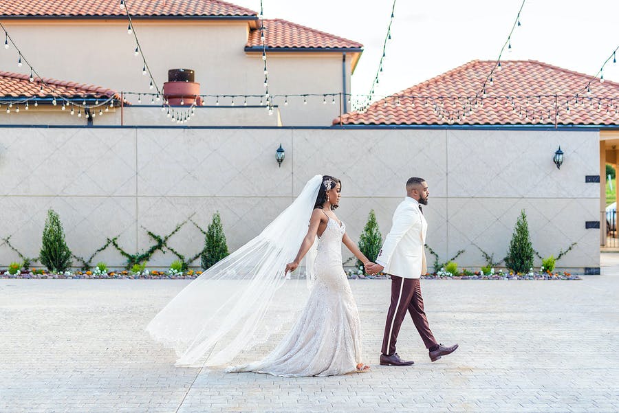Couple Walking Through Courtyard of D'Vine Grace Vineyard in McKinney Texas Wedding Venue | PartySlate