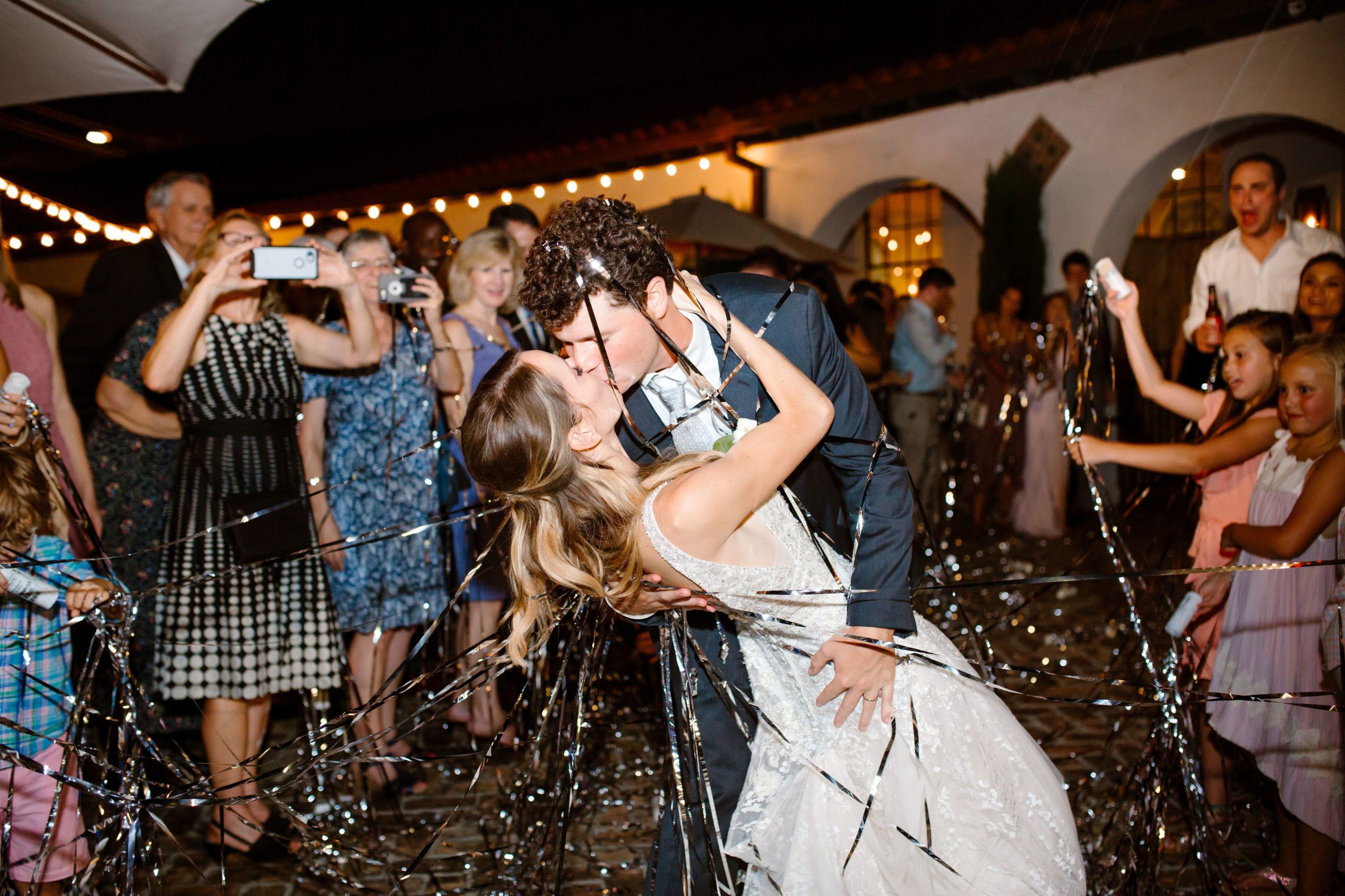 Classic New Orleans Wedding at Felicity Church and Il Mercato With Couple Kissing Surrounded By Streamers | PartySlate