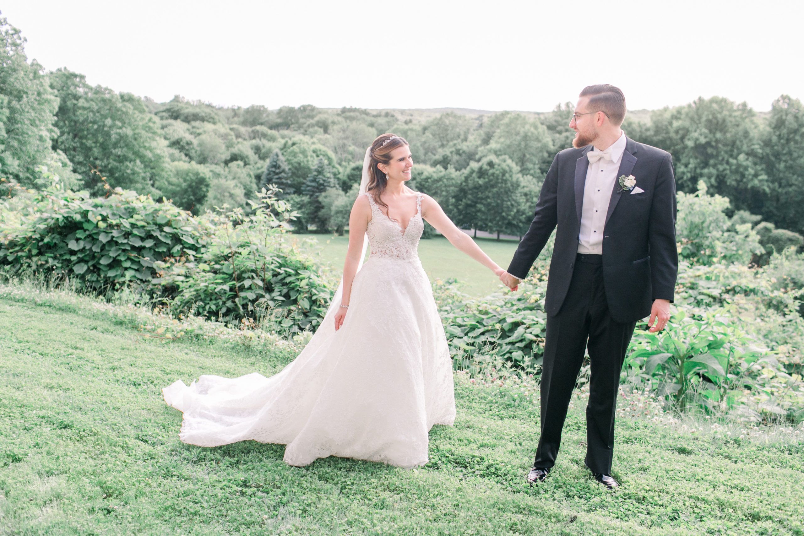 Dazzling Wedding at Le Chateau in South Salem, NY With Couple Standing in Green Grass Field With Hills Behind | PartySlate