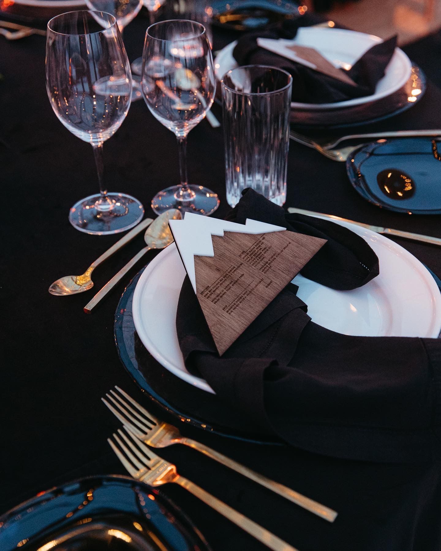 A menu shaped as a mountain on a black tablescape | PartySlate