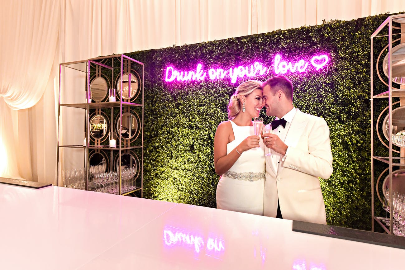 Wedding Bar with Cute Pink Neon Sign And Couple Making A Toast | PartySlate