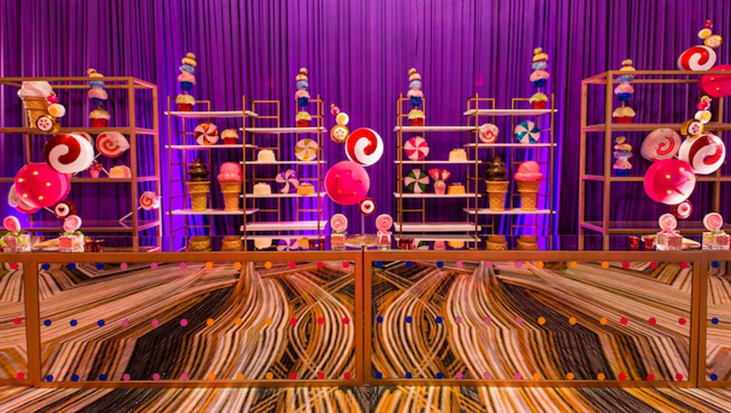 Candy theme party with a mirrored bar panels and stacked shelving filled with candy | PartySlate