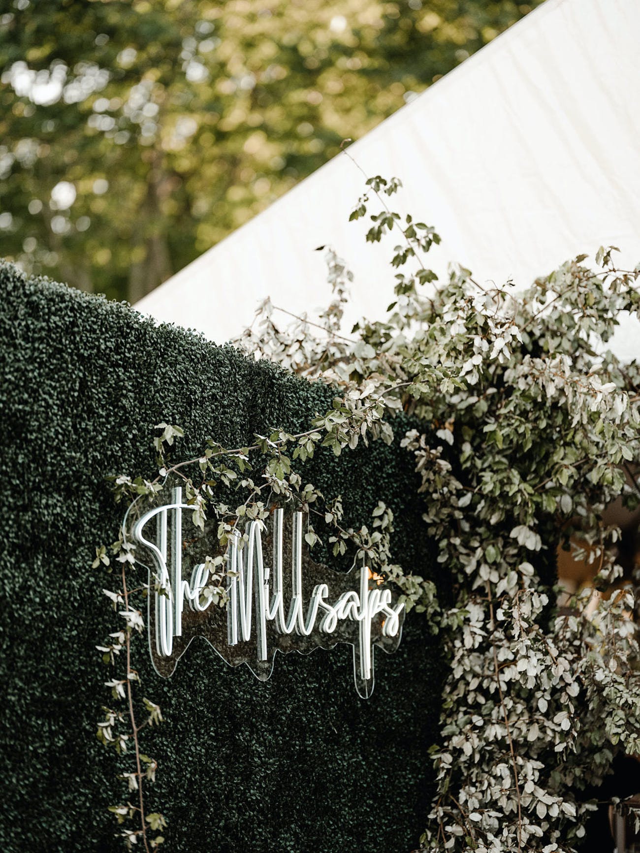 Couple Wedding Neon Sign on Greenery Wall Outside Venue | PartySlate