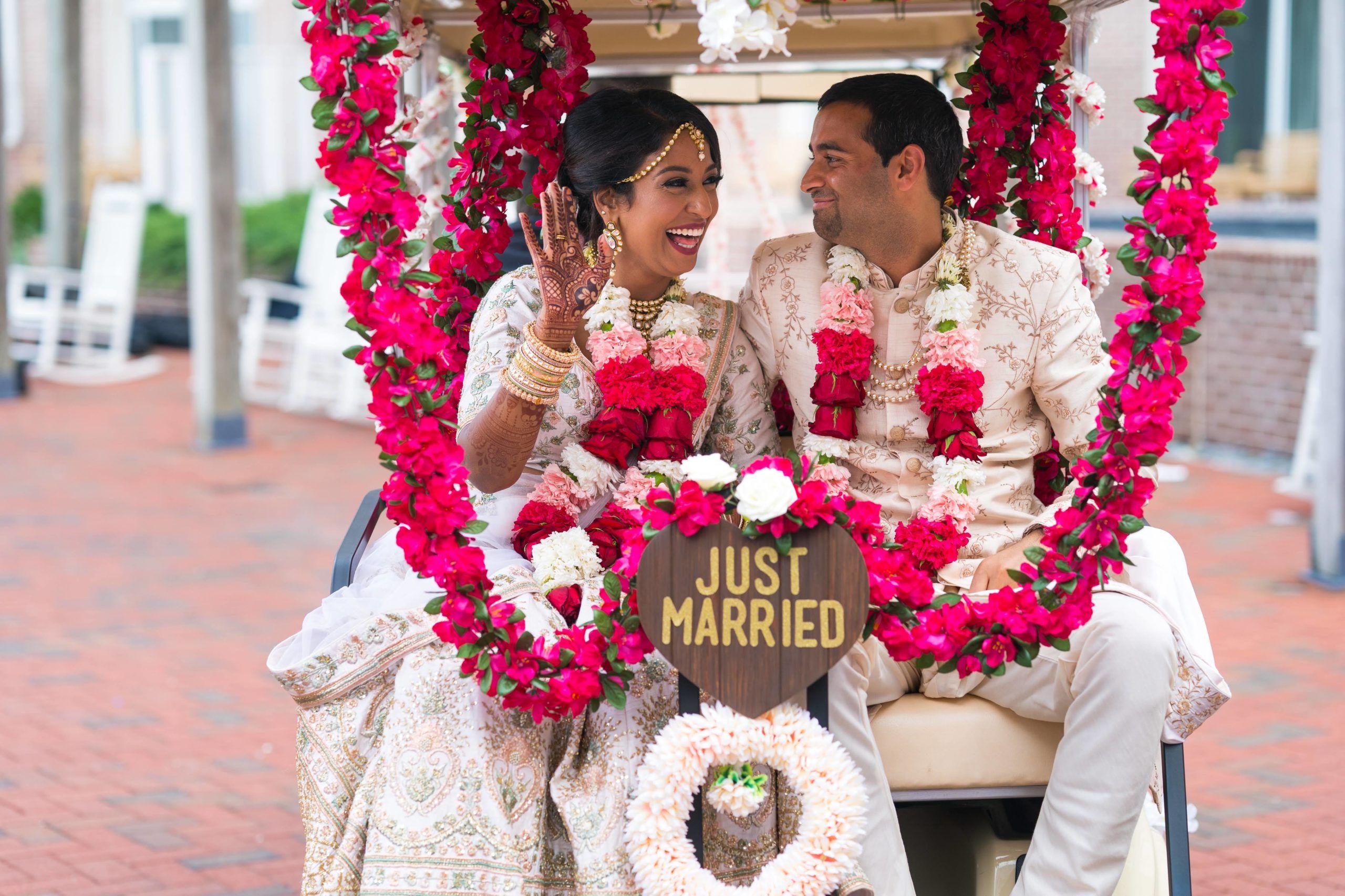 Couple Exiting Wedding Venue on Golf Cart Covered in Pink Florals | PartySlate