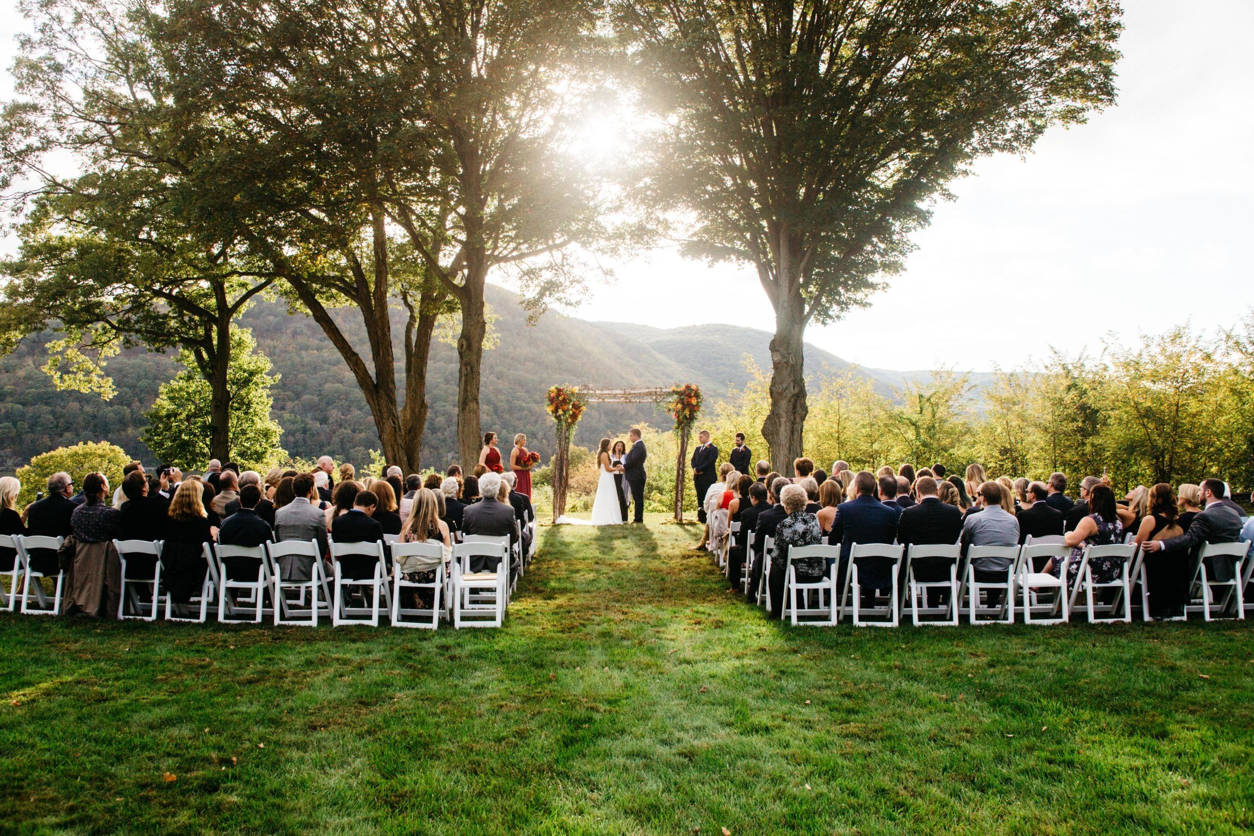 Stunning Outdoor Fall Wedding at Monteverde at Oldstone in Cortlandt Manor, New York With Couple At Alter With Sun Setting Behind | PartySlate