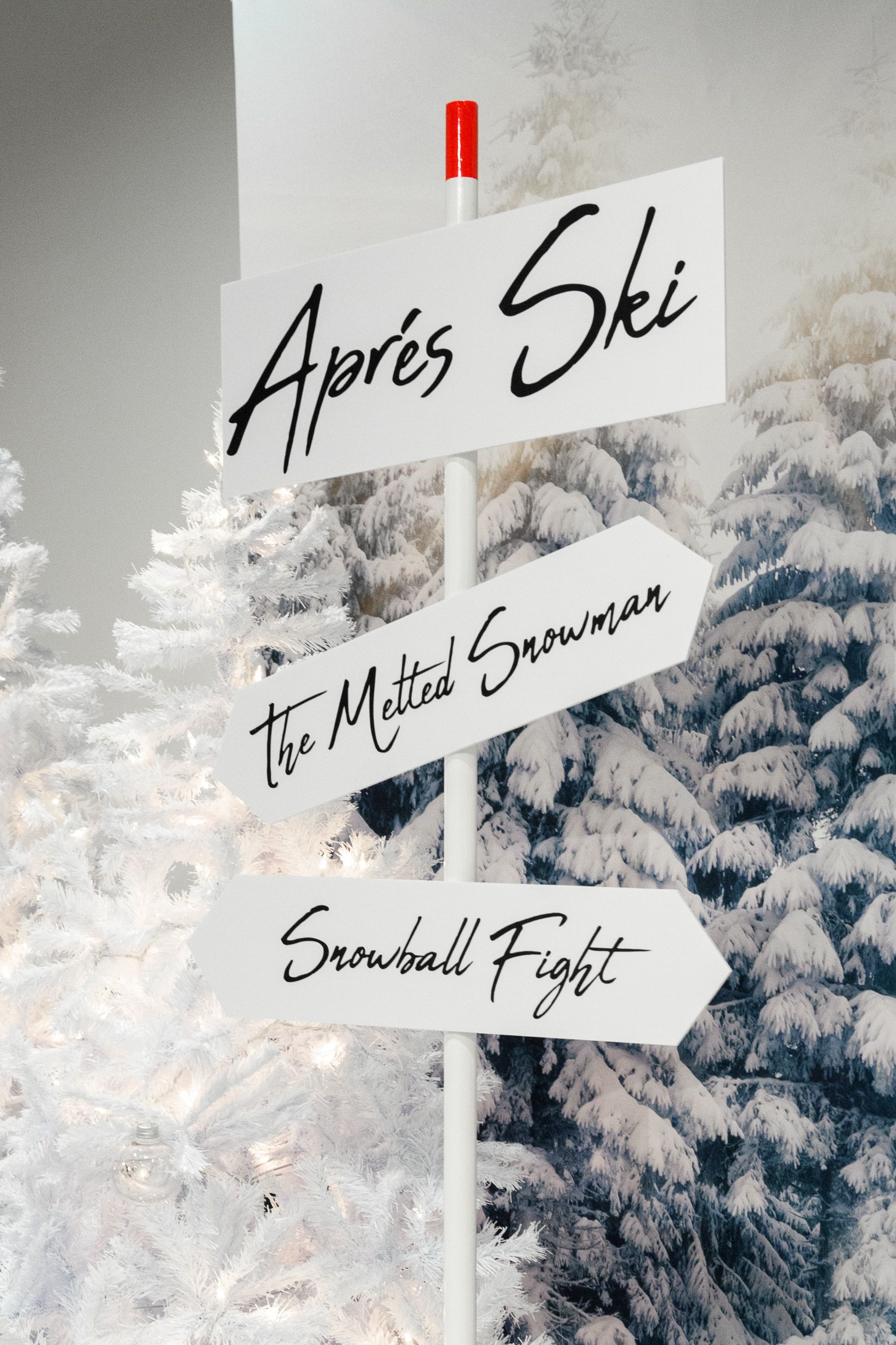 A white sign with different directions pointing to aprés ski, the matted snowman and snowball fight | PartySlate
