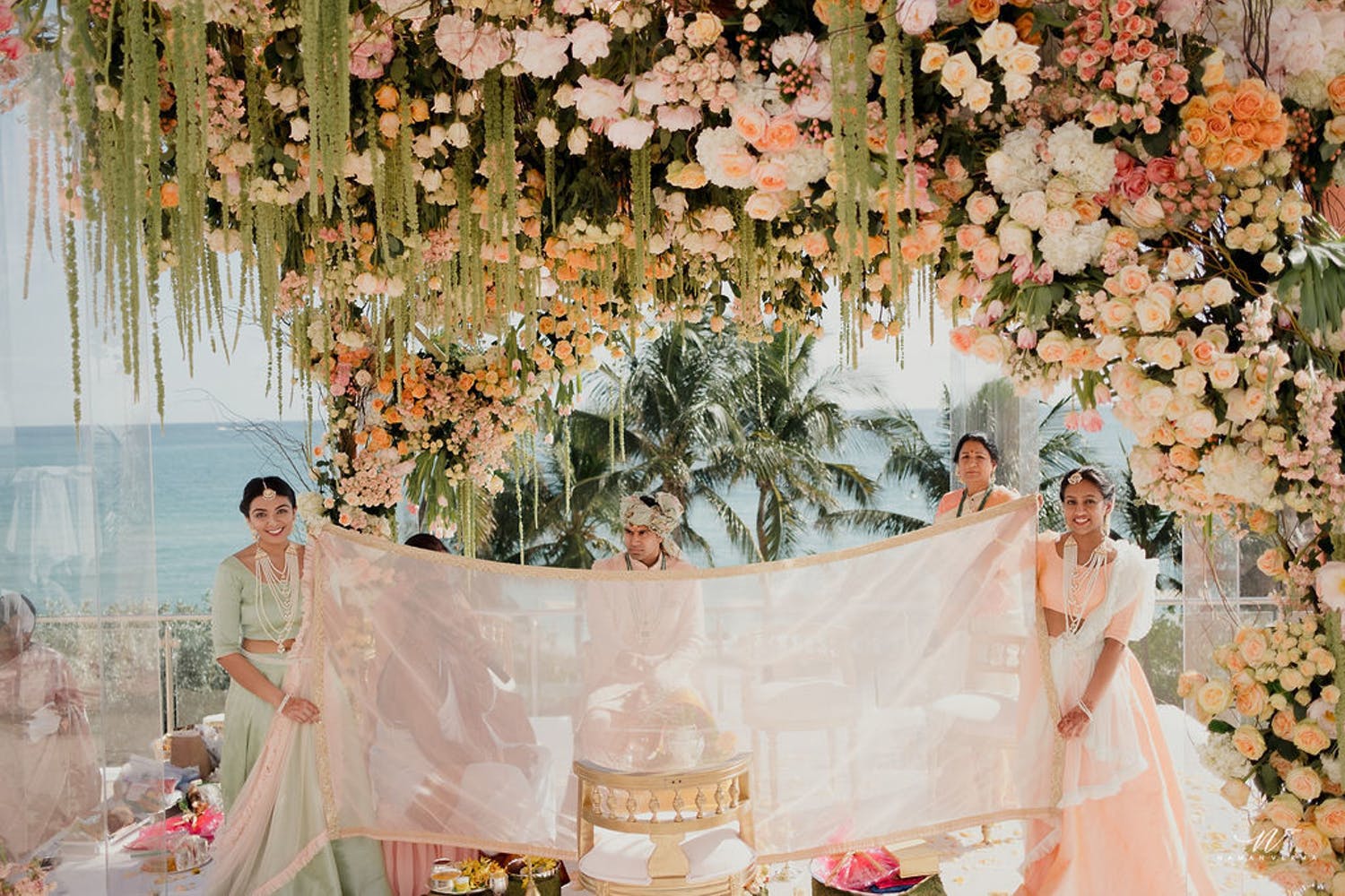 Beach wedding mandap with light orange and white florals with pink accents | PartySlate
