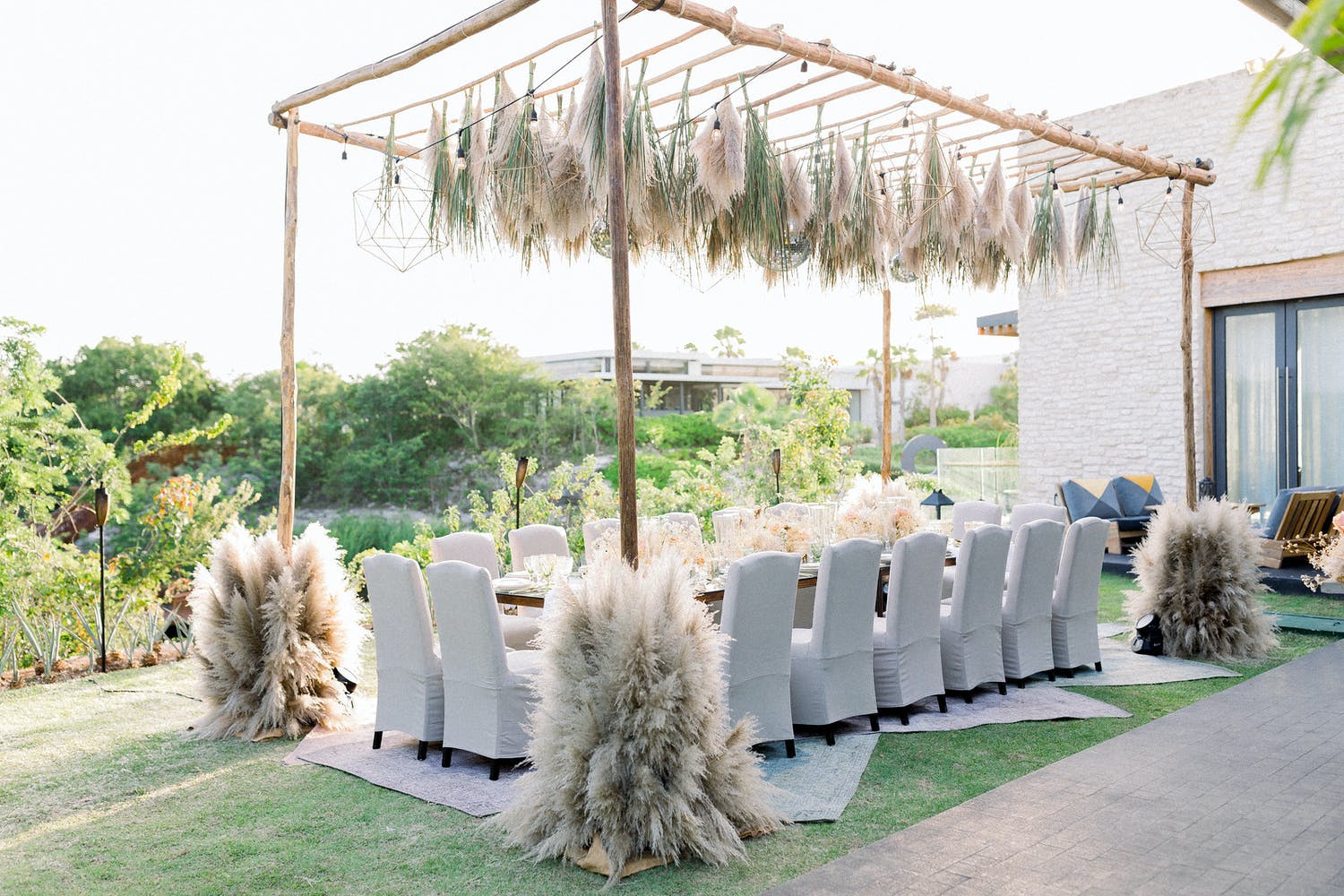 Outdoor wedding table with elevated and suspended pampas grass centerpieces | PartySlate